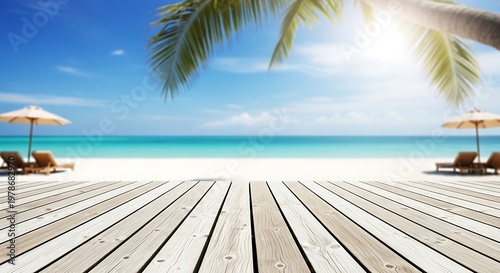 Wooden deck overlooking a beautiful tropical beach with palm tree and lounge chairs.