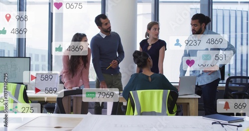 Diverse coworkers reviewing plans at office with laptop, turbine, safety vest and notifications