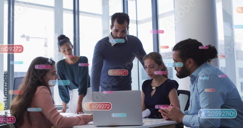Five business coworkers leaning and discussing around silver laptop in boardroom with data overlays