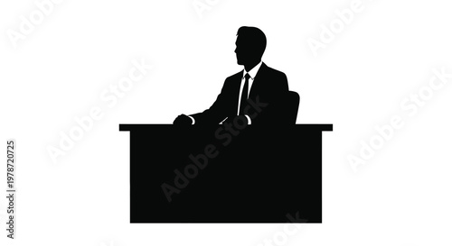 Silhouette of a man in a suit seated behind a desk