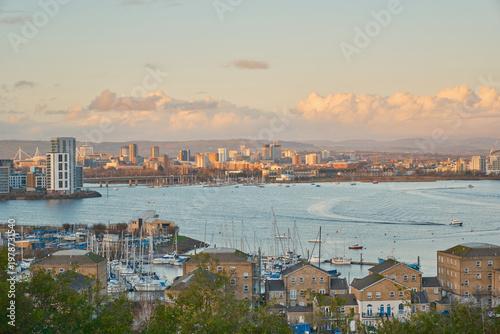 Fotografie Cardiff  skyline at golden hour, with Penarth Marina's yachts and waterside apartments in the foreground under a cloud-scattered sky
