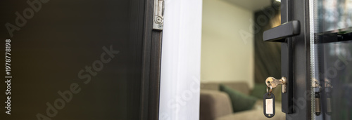 room door slightly ajar with a key left in the lock, revealing part of a cozy sofa inside, hinting at welcoming accommodation.