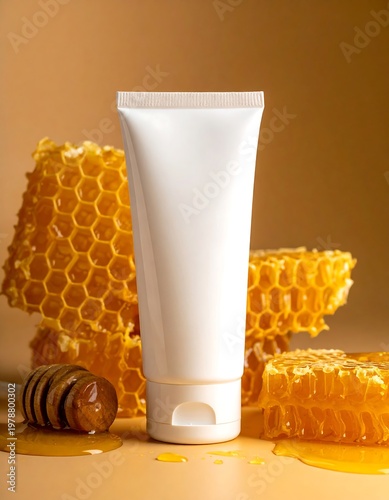 A white skincare tube stands with cut honeycomb and a honey dipper, showcasing a warm golden backdrop