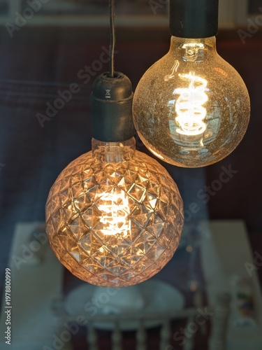 Two decorative vintage Edison light bulbs glowing warmly with intricate filament patterns in a dim room
