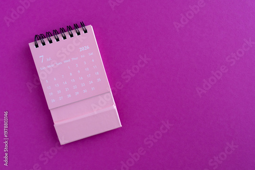 Desk calendar for July 2026 on a bright pink background with copy space.