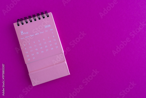 Desk calendar for August 2026 on a bright pink background with copy space.