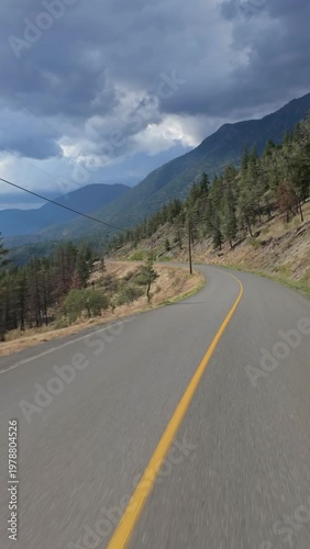 Scenic Drive Through British Columbia's Mountainous Forest Road Under Dramatic Cloudy Skies