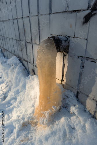 Фотография Rusty water froze in a drainpipe during a cold winter