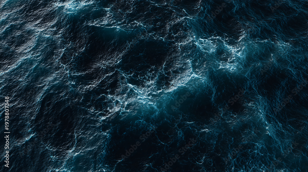 Fototapeta premium A close-up view of turbulent ocean waters, showcasing deep blue hues and dynamic wave patterns illuminated by light reflections.