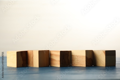 Blank cubes on blue wooden table, space for text