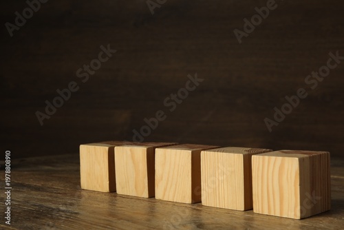 Blank cubes on wooden table, space for text