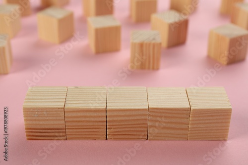 Many blank wooden cubes on pink background, space for text