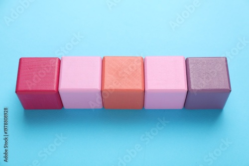 Empty colorful cubes on light blue background, above view. Space for text