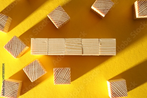 Many blank wooden cubes on yellow background, flat lay. Space for text