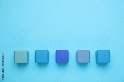 Empty wooden cubes on light blue background, flat lay. Space for text