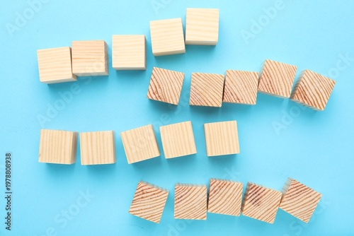 Empty wooden cubes on light blue background, flat lay. Space for text