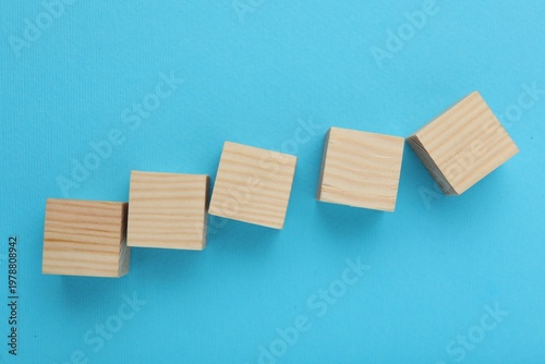 Empty wooden cubes on light blue background, flat lay. Space for text
