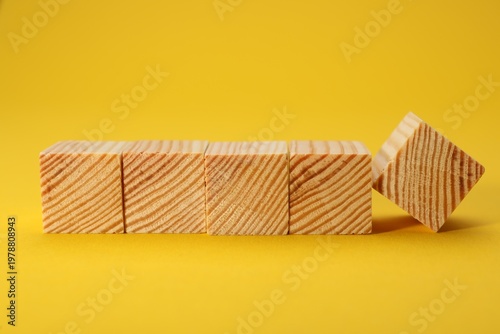 Many empty wooden cubes on yellow background, space for text