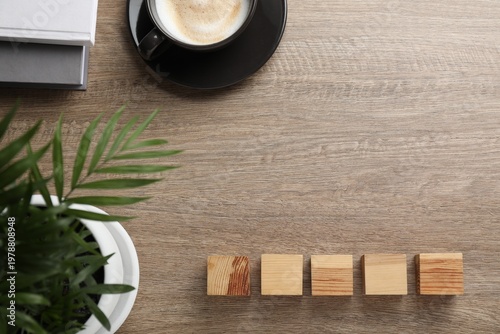 Empty wooden cubes near potted houseplant and cup of coffee on table, flat lay. Space for text