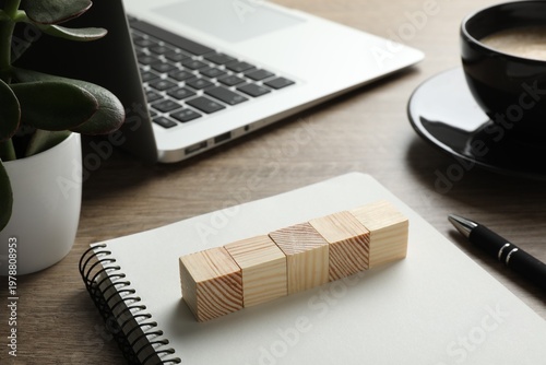 Empty wooden cubes near laptop and notebook on table, space for text