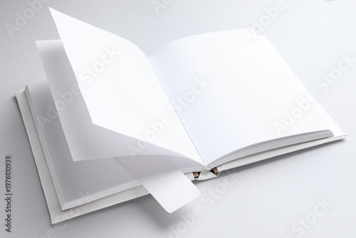 Book with white bookmark on light grey background, closeup. Space for text