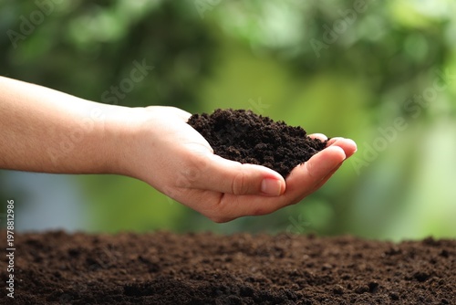 Woman with fresh soil on blurred background, closeup