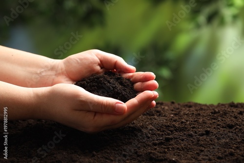Woman with fresh soil on blurred background, closeup