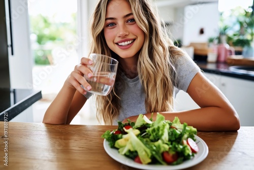 Young Woman Enjoys a Salad and Water at Her Kitchen Table in a Bright Setting