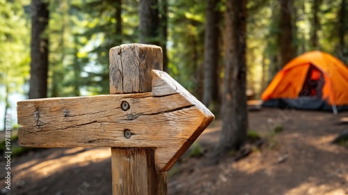 Wooden Sign Points Right Towards an Orange Camping Tent in a Forest Setting N...