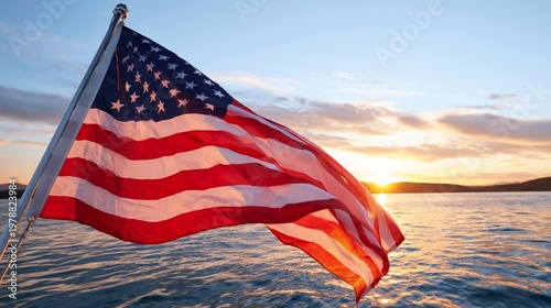 American Flag Waves by the Water During Sunset Near a Mountain Landscape in a...