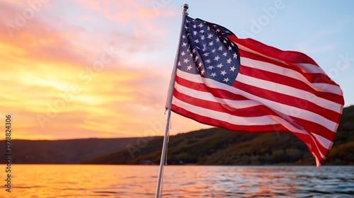 American Flag Waves by the Water During Sunset Near a Mountain Landscape in a...