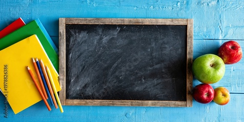 School Supplies on a Blue Table With a Blank Chalkboard and Apples