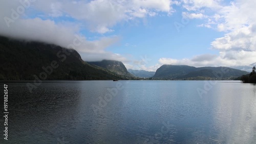 lake bohinj with mountains background (aerial view of famous alpine travel destination in slovenia) boat kayaking scenic european tourism getaway (julian alps, europe) rain view scenic landscape