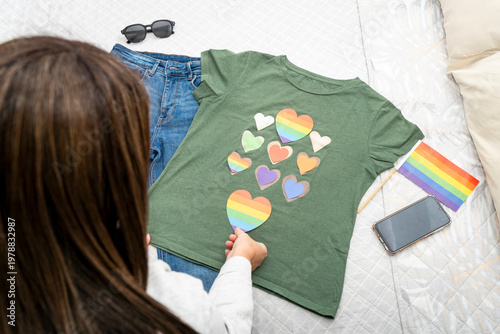 Person preparing clothing with rainbow hearts for a pride celebration
