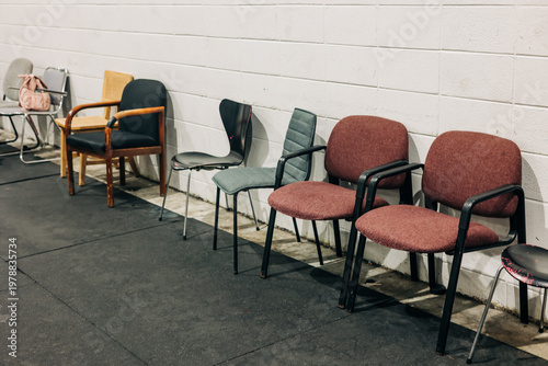 Different types of chairs lined against a wall in a simple room with a flat floor
