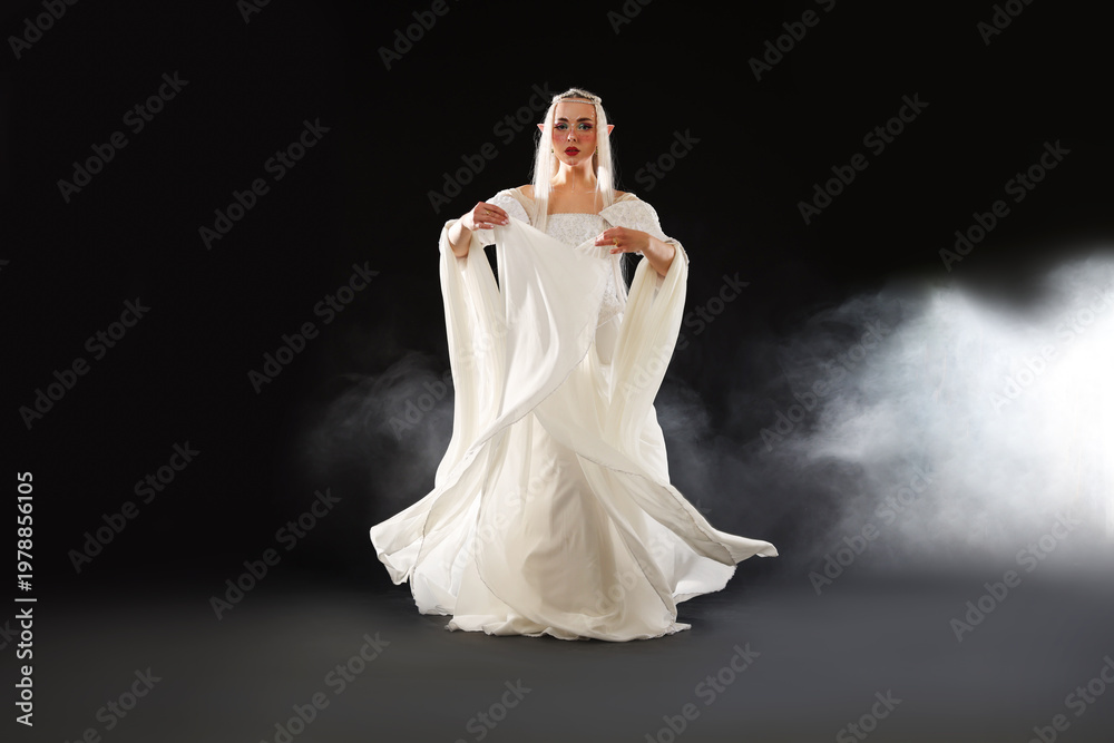Naklejka premium Beautiful girl dressed as elf on black background with smoke