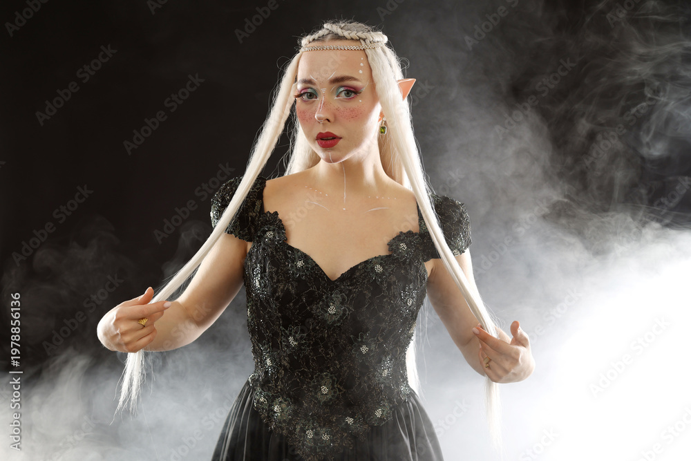 Naklejka premium Beautiful girl dressed as elf on black background with smoke