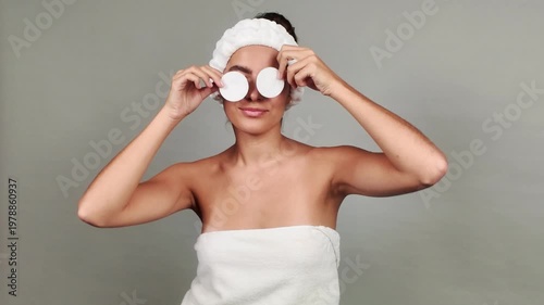 Playful woman holding cotton pads during beauty routine
