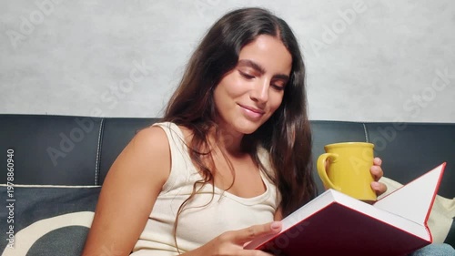 Beautiful young woman smiling while reading a book