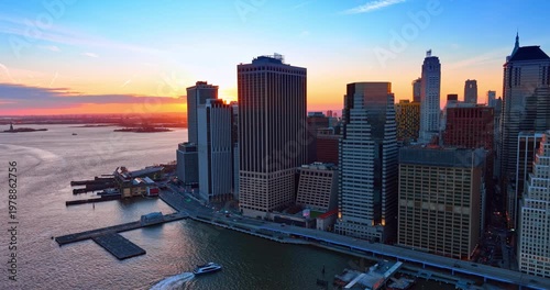 Setting sun seen behind the high-rises at the river waterfront. Drone footage over the waterscape in New York City, USA.