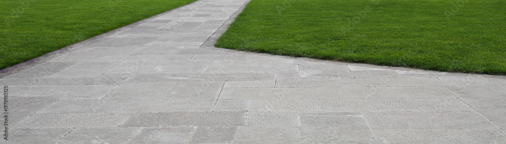 Obraz premium path in the shape of a wave on green grass in the Park Paved with tiles gray brick stone pavement creates a unique perspective view on the ground, perfect for street roads, sidewalks, and driveways,