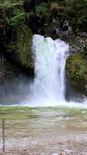 beautiful scenic small waterfall in forest next to farm river and bike trail in bohinj slovenia europe (stunning landscape julian alps alpine mountains scenery) trees woods hiking hike path trail