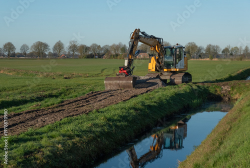 Excavator spreading dredge on field from cleaning a ditch