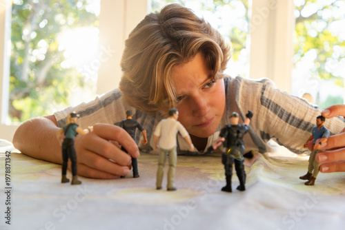 12 year old boy playing with toy soldiers at home
