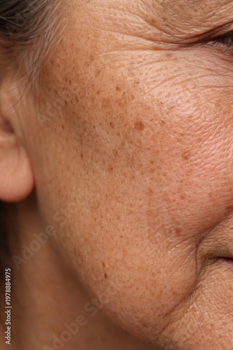 Close-up of mature woman's face showcasing skin texture and beauty. Natural aging process highlights unique features. Perfect for wellness and skincare marketing. Vertical composition enhances focus.