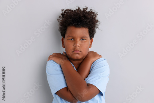 Photos Portrait of resentful little boy with crossed arms on grey background