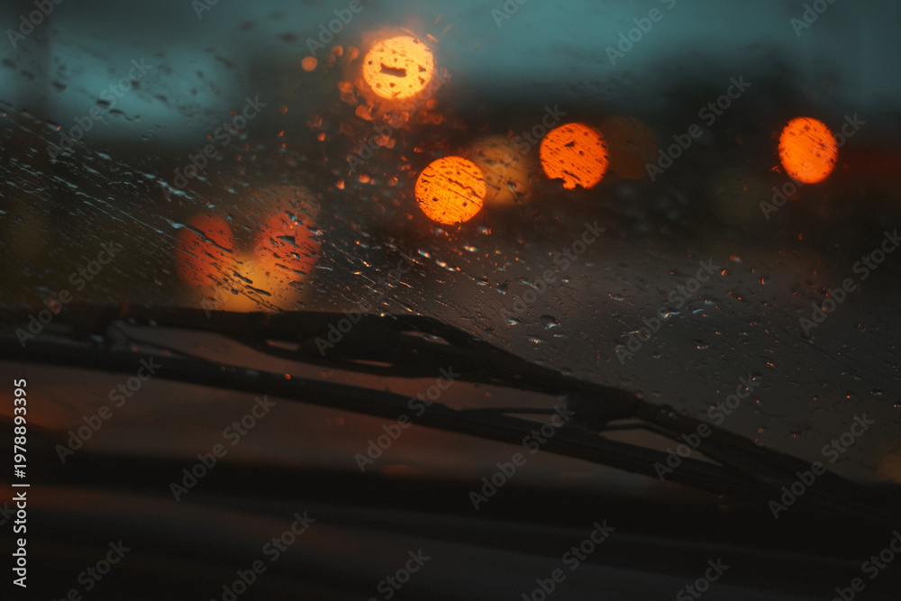 Obraz premium A rainy night drive through the city with blurred traffic lights ahead