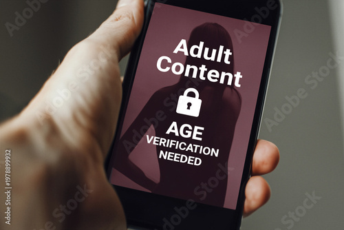 close up of a male hand holding a mobile device the screen is displaying a silhouette of a woman with the words Adult Content Age Verification needed and a padlock icon