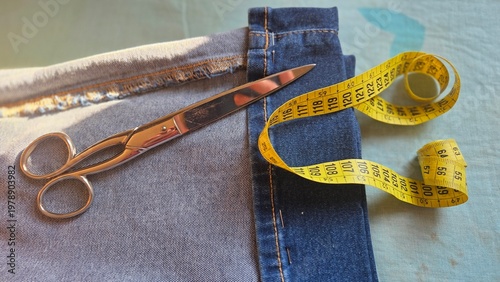 Quadro em tela Overhead view of denim jeans with scissors and curled yellow measuring tape for