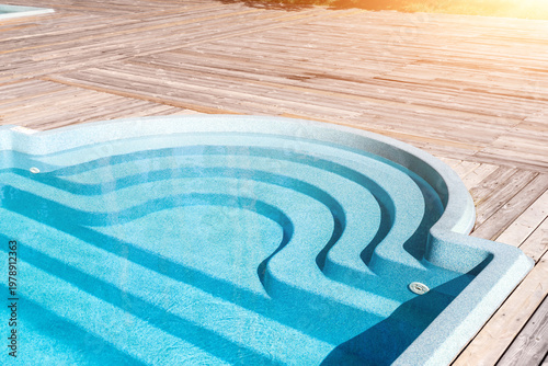 Cuadro en lienzo New modern fiberglass plastic swimming pool entrance step with clean fresh refreshing blue water on bright hot summer day at yard or resort hotel spa area